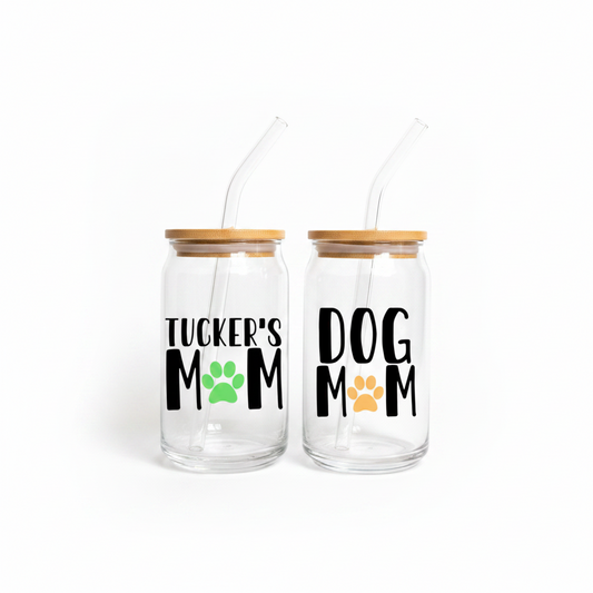 Two glass jars with wooden lids, one labeled 'Tucker's Mom' with a green paw print, the other labeled 'Dog Mom' with an orange paw print, on a white background.