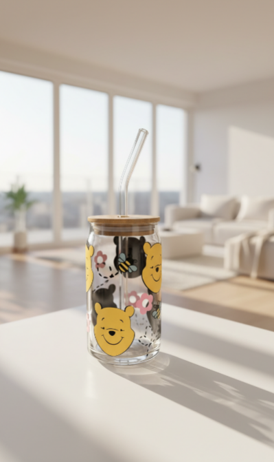 Clear glass tumbler with Winnie the Pooh design on a white surface in a bright room.